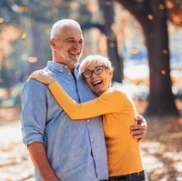 An older couple hugging and laughing while having fun outdoors after seeing their Delta Dental dentist in Castle Hills