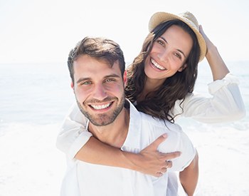 young couple on beach smiling after getting teeth whitening in San Antonio 