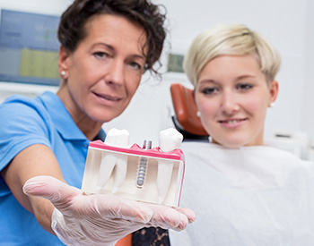 Dentist showing female patient implant model