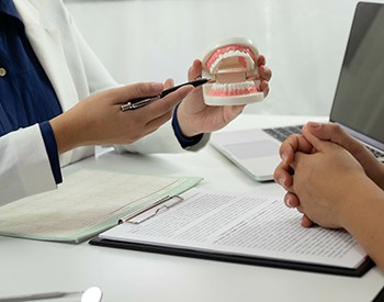 Dentist pointing to a model of teeth at a desk