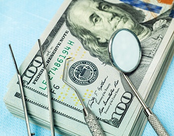 Dental instruments resting on a stack of money