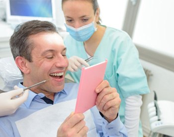 man admiring his new smile after getting dental implants 	