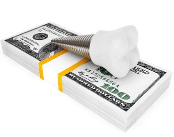 model dental implant on a stack of money  	