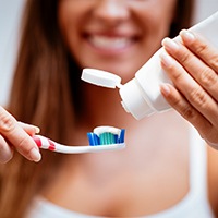 Woman applying toothpaste to a toothbrush