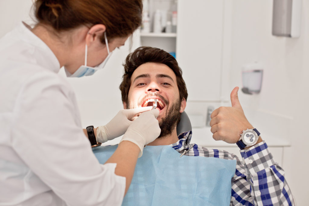 man smiling thumbs up dentist chair