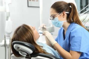 family dentist in Castle Hills examining patient’s mouth 