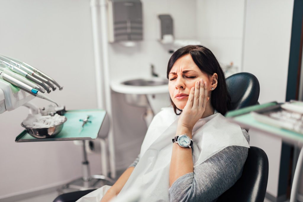 woman with toothache in San Antonio holding cheek at dentist 