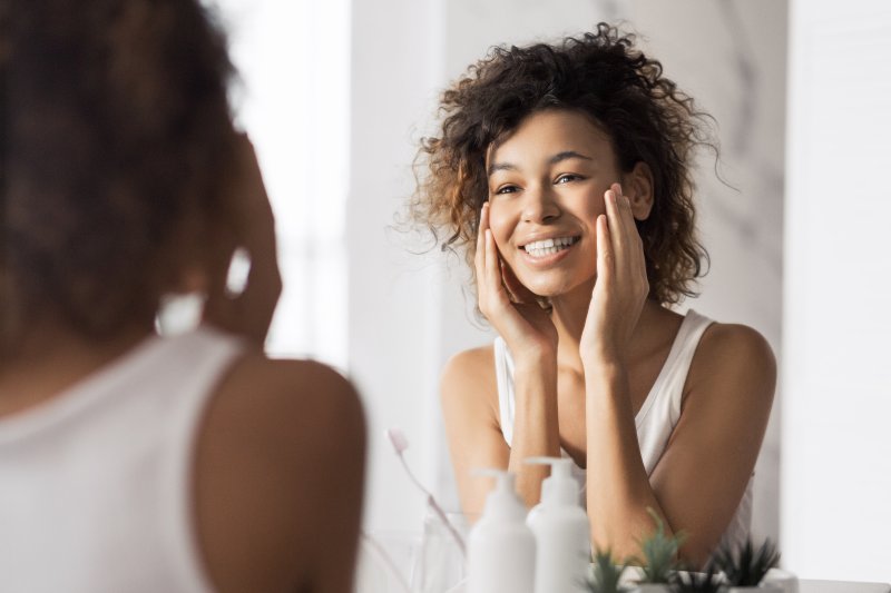 Patient smiling in the mirror after getting porcelain veneers